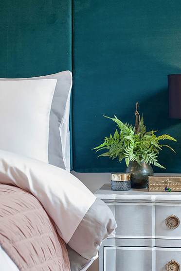 Close up of the sleeping corner of a bed and a table lamp