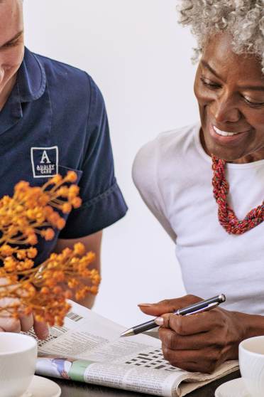 Woman solving crossword with carer
