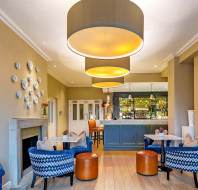 Bistro with blue armchairs, caramel leather stools and beige walls