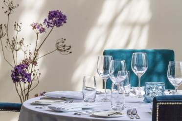 Table set for dinner at Whittle's Restaurant, Audley Binswood Table setting with purple flowers and plush blue chairs